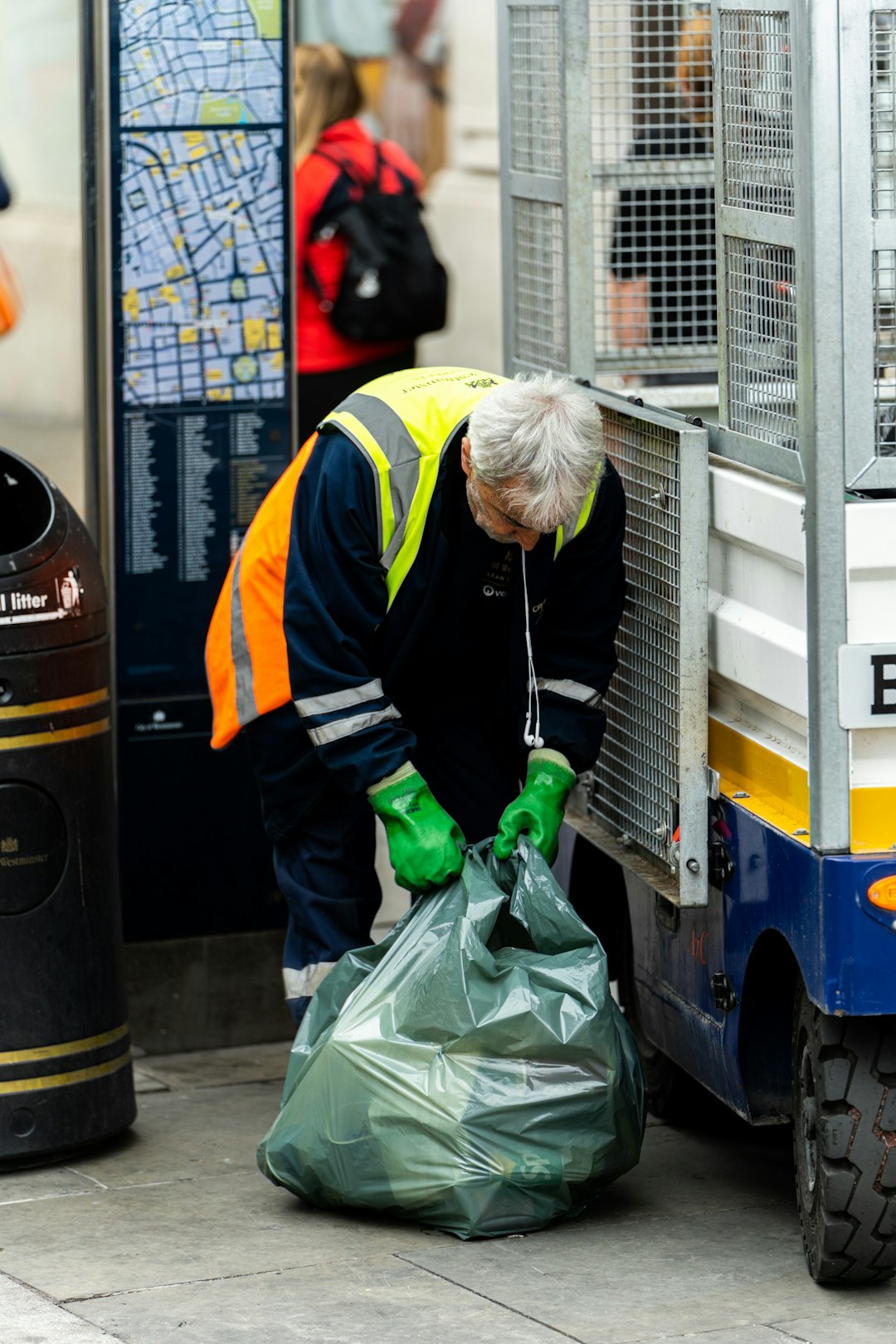 our-story a-man-in-a-yellow-safety-vest-and-green-gloves-unloads-a-garbage-bag-pjhxjgl-hhi